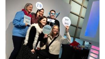 Carolina employees pose with signs at photo booth